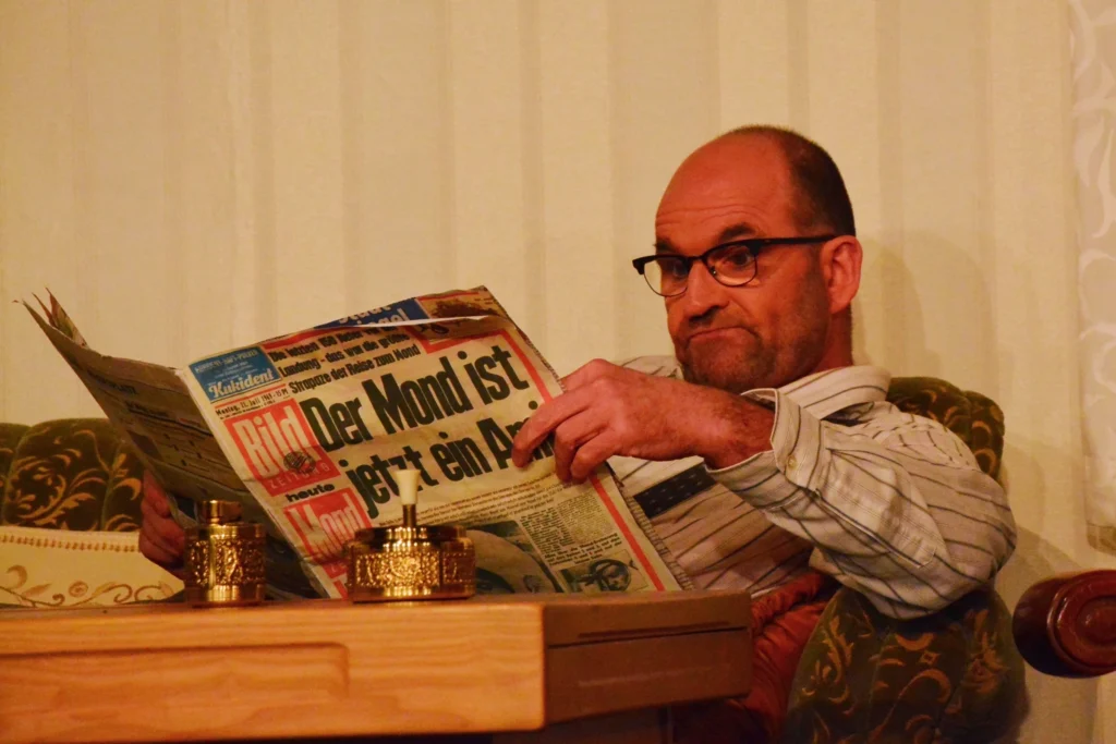 Ein Mann mit Brille liest im Sessel eine großformatige Zeitung